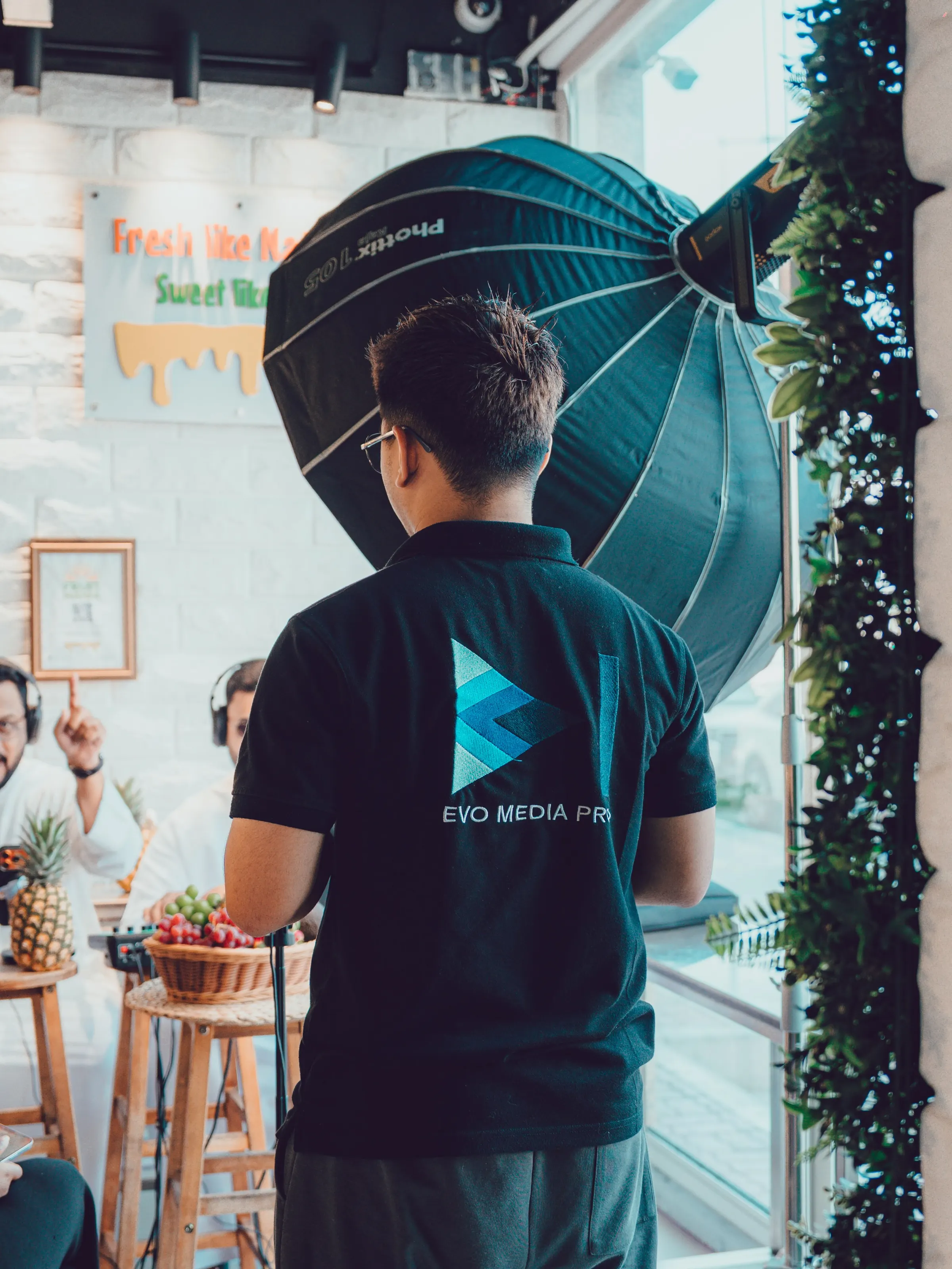 A crew member in an Evo Media Pro shirt adjusting a softbox on a podcast set