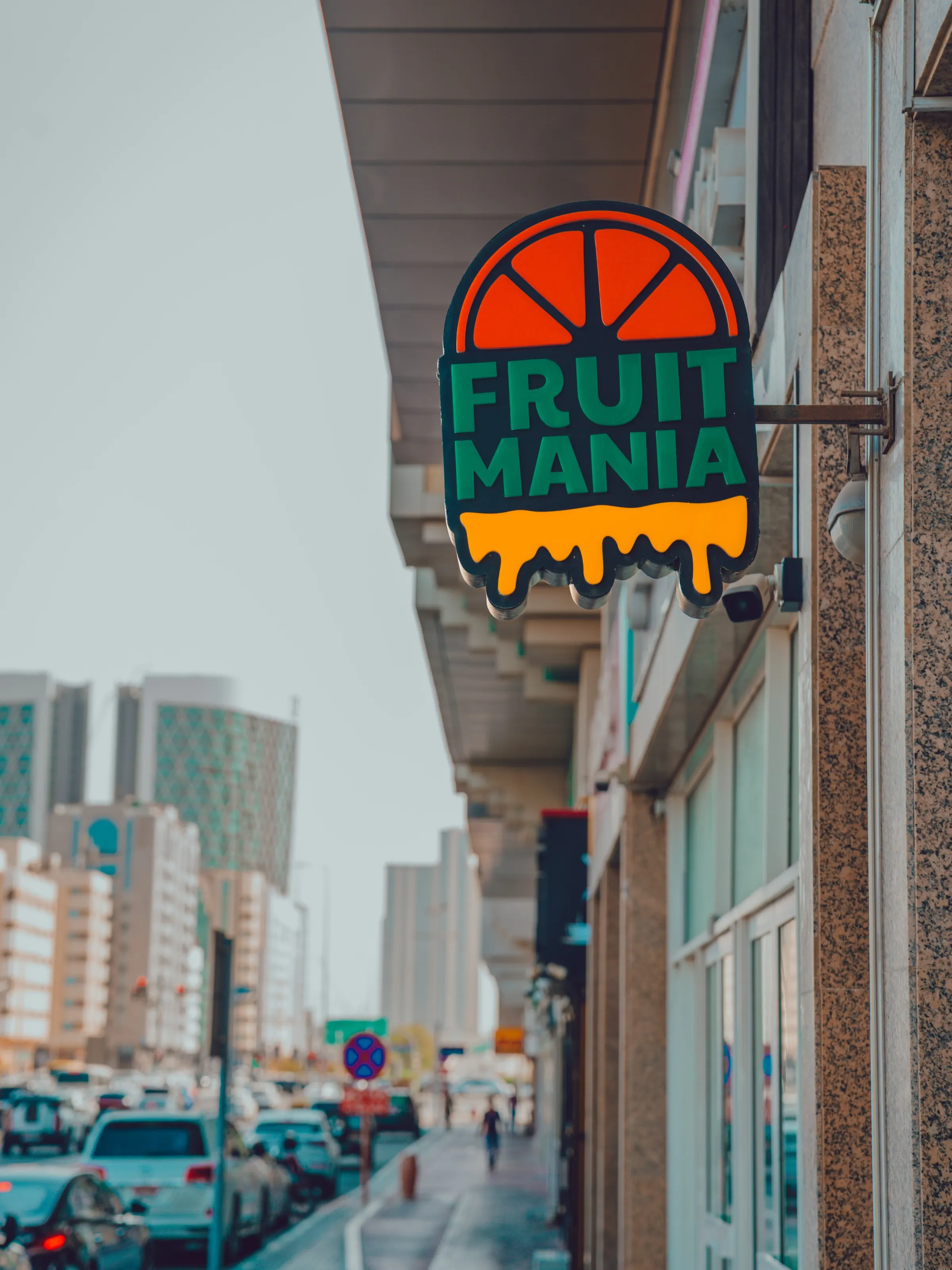 A street view of a venue frontage with illuminated signage, city buildings behind