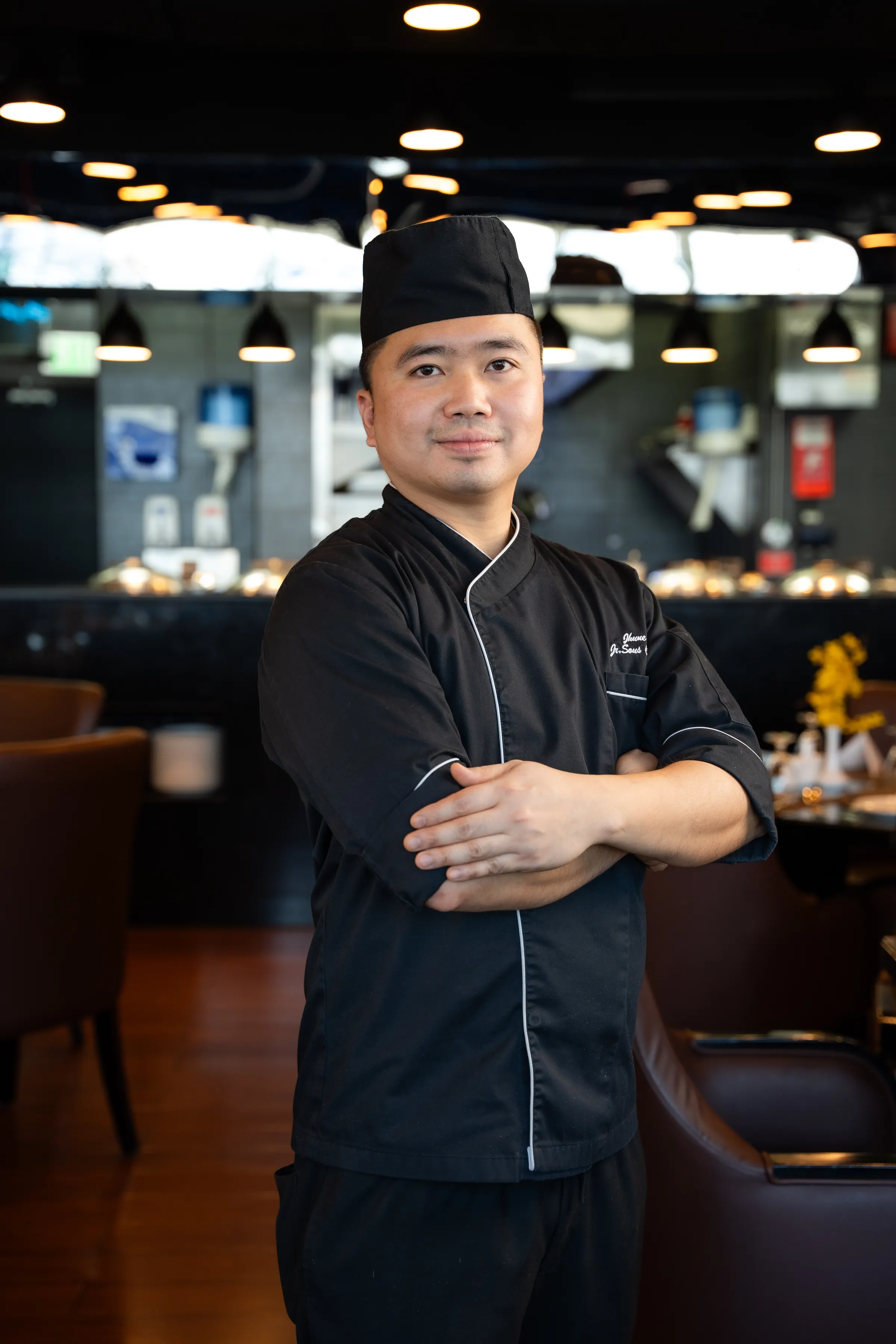 Chef standing with arms folded in a restaurant dining room
